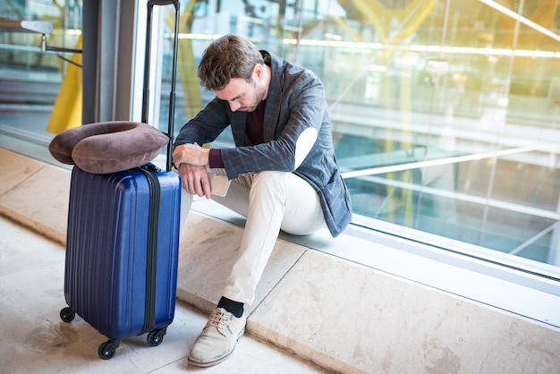 Mann aufgeregt, traurig und wütend am Flughafen ist sein Flug verspätet