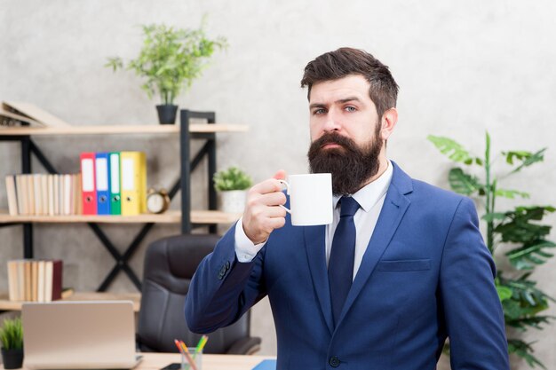 Mann bärtiger Geschäftsmann halten Kaffeetasse stehen Bürohintergrund Kaffeetrinken entspannende Pause Boss genießt Energy-Drink Erfolgreiche Menschen trinken Kaffee Koffeinsüchtig Beginnen Sie den Tag mit Kaffee