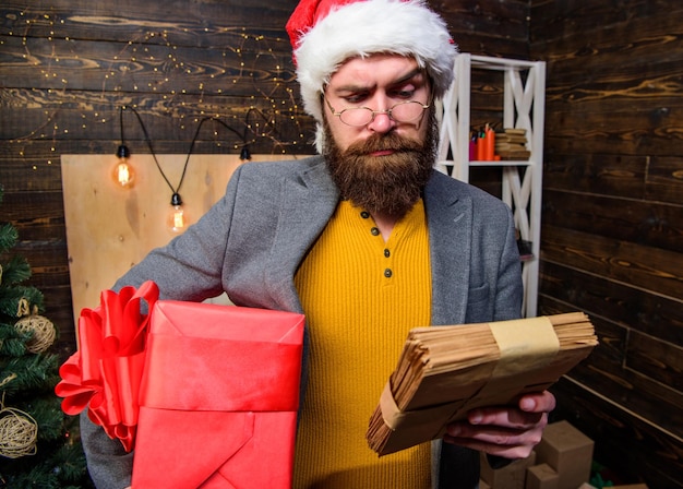 Mann bärtiger Hipster trägt Weihnachtsmütze hält Haufen Briefe und Geschenkbox Geschenklieferdienst Brief für den Weihnachtsmann Mann, reifer Bärtiger mit Brille, erhielt Post für den Weihnachtsmann Post für den Weihnachtsmann