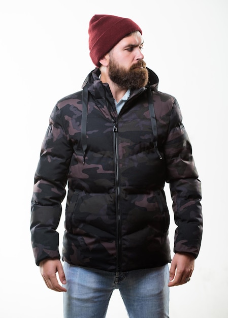 Foto mann bärtiger stand warm tarnmuster jacke parka isoliert auf weißem hintergrund hipster wintermode guy trägt hut und schwarze winterjacke bequemes winteroutfit winter stilvolle herrenbekleidung