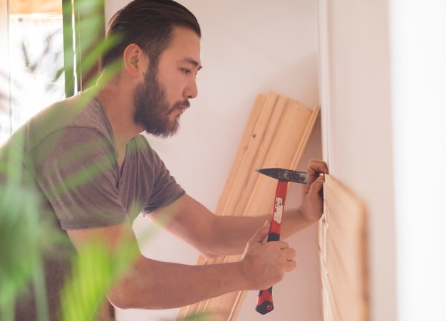 Mann baut ein Haus und arbeitet mit Hammer und Holz