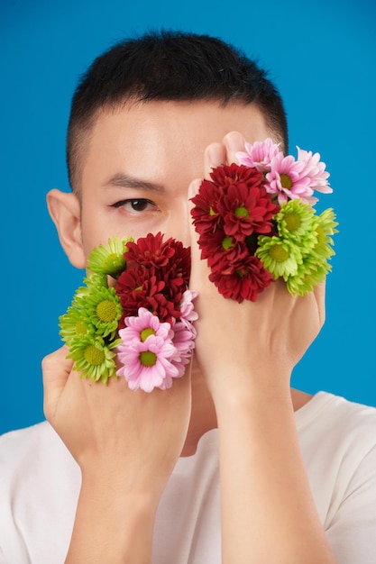 Mann bedeckt Gesicht mit Blumen