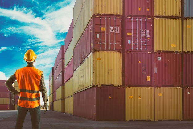 Mann bei der Arbeit zwischen Containern in einem Handelshafen