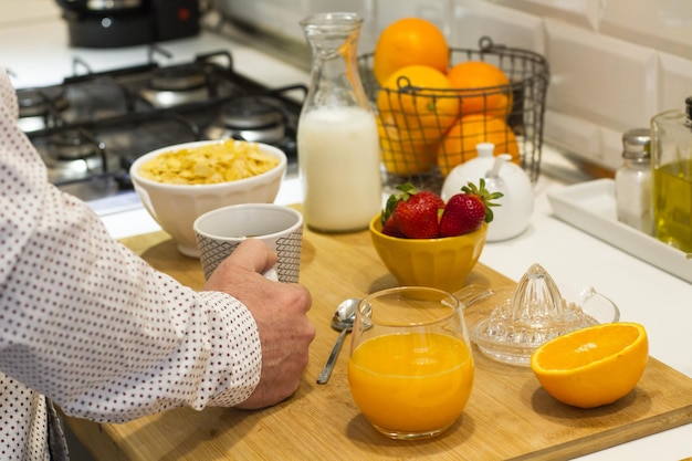 Mann beim Frühstück mit einer Tasse Kaffee und Orangensaft