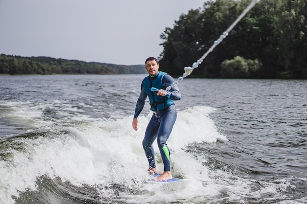 Mann beim Wakesurfen. winken vom Boot.