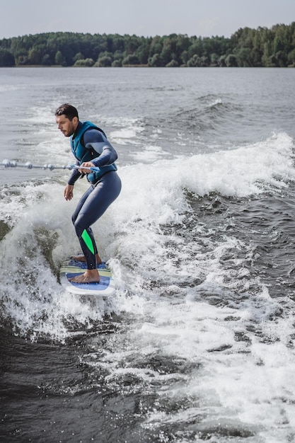 Mann beim Wakesurfen. winken vom Boot.