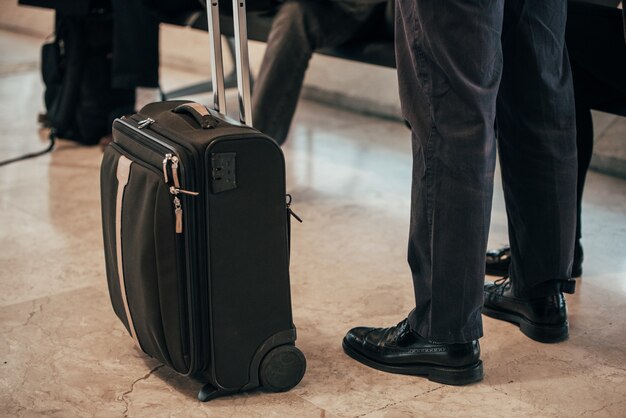 Mann Beine stehendes Gepäck am Flughafen