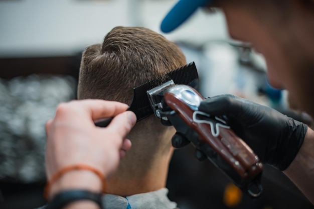 Mann bekommt einen coolen Haarschnitt im Friseursalon. Barber macht den Cut Man Elektrorasierer. Pflegekopf der Männer. Weicher Fokus.