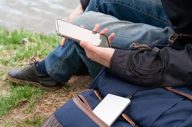 Mann benutzt Smartphone am Ufer des Flusses