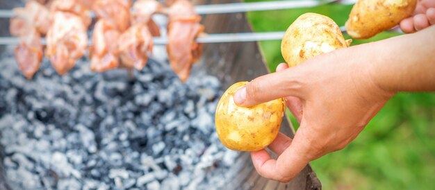 Mann bereitet Grillfleisch mit Kartoffeln vor