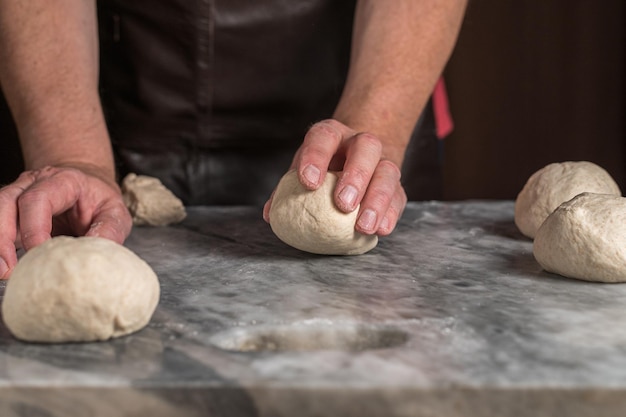 Mann bereitet Pizzateig auf Marmortisch zu