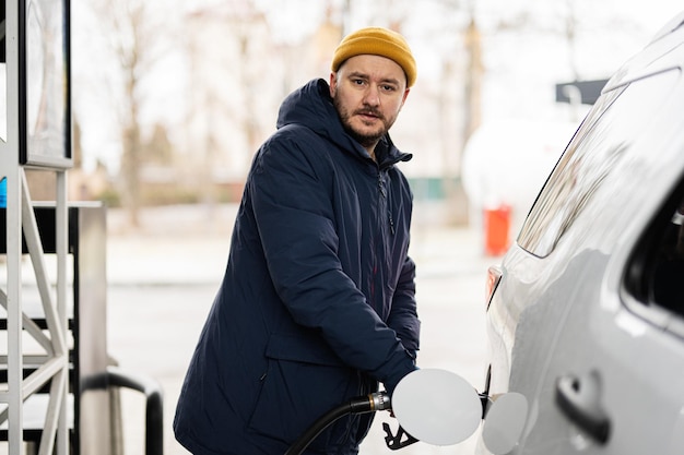 Mann betankt sein amerikanisches SUV-Auto an der Tankstelle bei kaltem Wetter