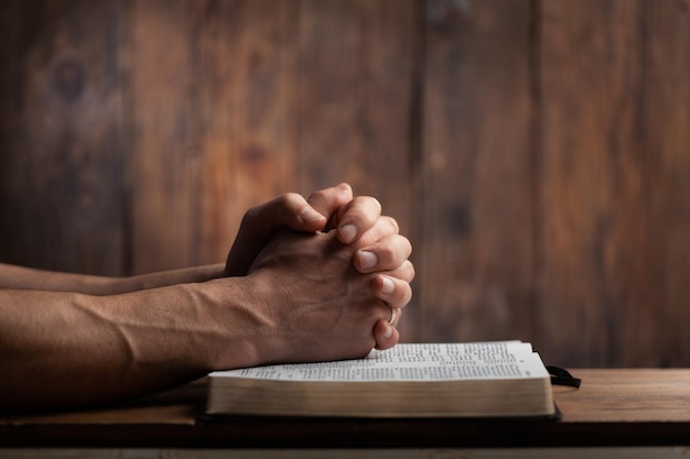 Mann betet mit den Händen auf der Bibel Konzept Religion