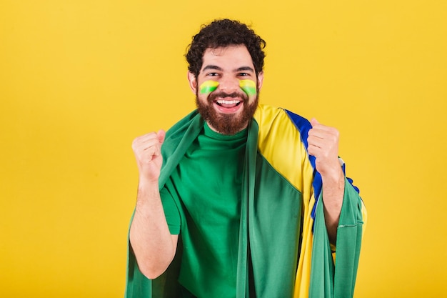 Mann brasilianischer bärtiger fußballfan aus brasilien mit schaumfinger und horn feiert im fußballspiel