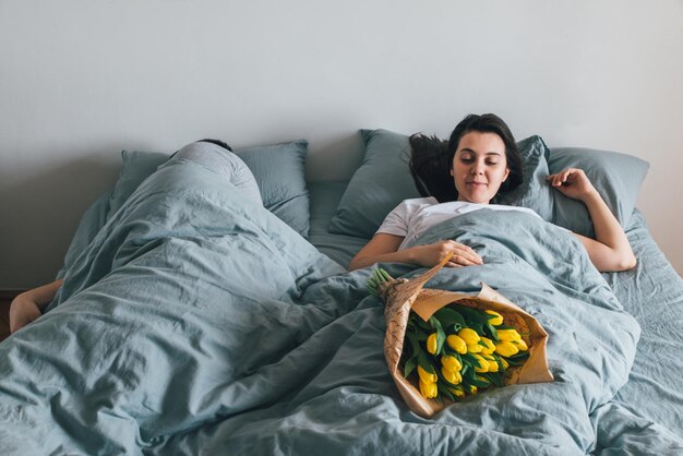 Mann bringt Blumen ins Bett. Überraschung für Freundin am Morgen. romantisches Konzept