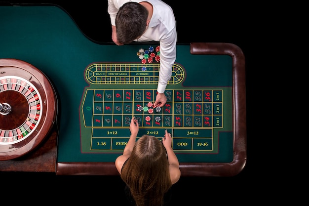 Mann-Croupier und Frau, die Roulette am Tisch im Casino spielen. Draufsicht an einem grünen Roulettetisch mit einem Maßband. Tisch für Glücksspiele in einem Luxus-Casino. Glücksspiel. Casino-Roulette