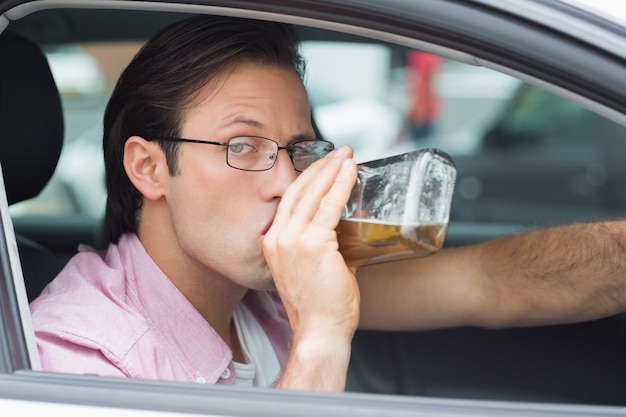 Mann, der Alkohol beim Fahren trinkt