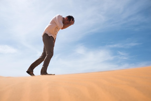 Mann, der allein in der sonnigen Wüste spazieren geht. Er ist verloren und außer Atem. Kein Wasser und keine Energie