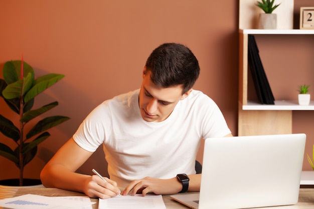 Mann, der am Computer im Büro arbeitet und Dokumente füllt