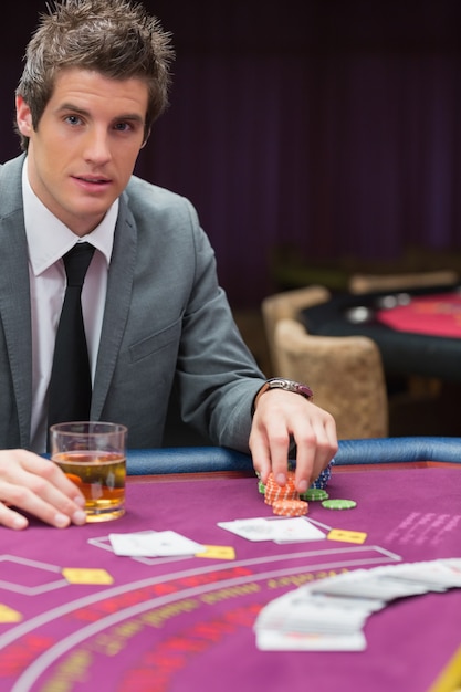 Mann, der am Pokertisch mit Whisky sitzt