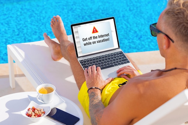 Mann, der am Pool sitzt und im Urlaub einen Laptop benutzt