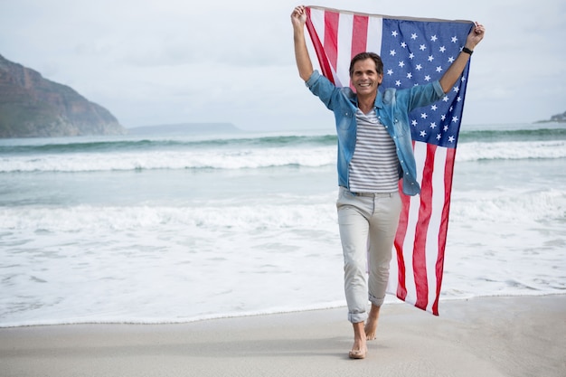 Mann, der amerikanische Flagge am Strand hält