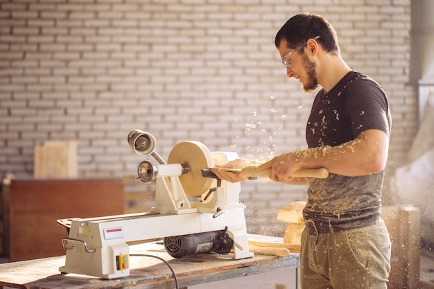 Mann, der an der kleinen Holzdrehmaschine arbeitet, ein Handwerker schnitzt Stück Holz