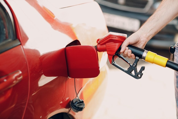 Mann, der an der Tankstelle die Füllpistole in der Hand hält