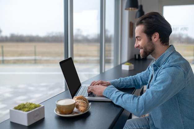 Mann, der an einem Laptop arbeitet, der seitlich zur Kamera sitzt