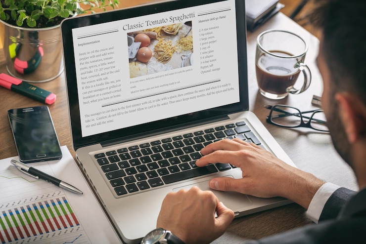 Foto mann, der an einem laptop-rezept auf dem bildschirm arbeitet
