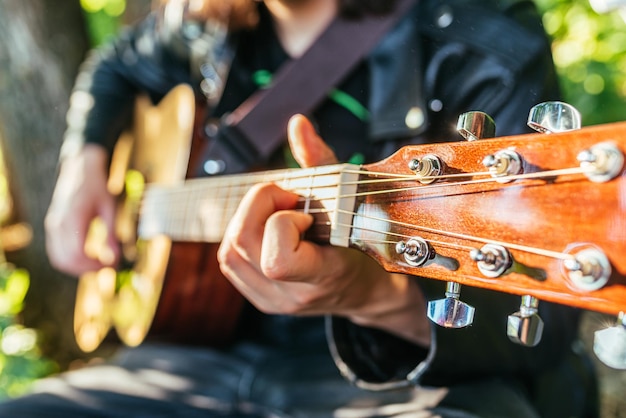 Mann, der an einem sonnigen Tag Gitarre in der Natur spielt