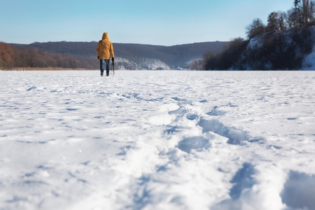 Mann, der an einem sonnigen Wintertag durch den Schnee geht Blick von hinten