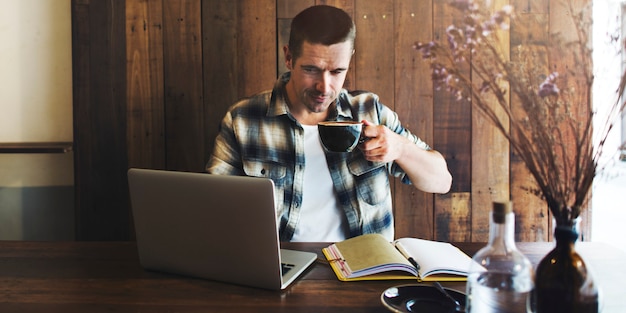 Mann, der an seinem Laptop arbeitet und Kaffee trinkt