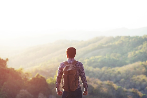 Mann, der an Sonnenuntergangsbergen mit schwerem Rucksack reist Lebensstil Fernweh-Abenteuerkonzept Sommer