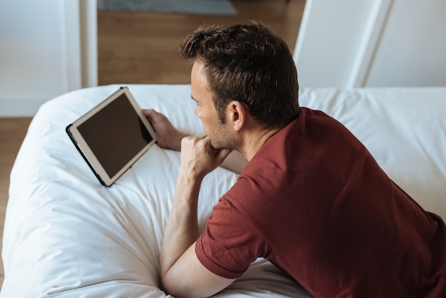 Mann, der auf Bett mit Tablette liegt