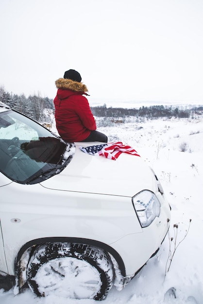 Mann, der auf der motorhaube des suv-autos mit usa-flagge sitzt. Autoreisekonzept. Lebensstil