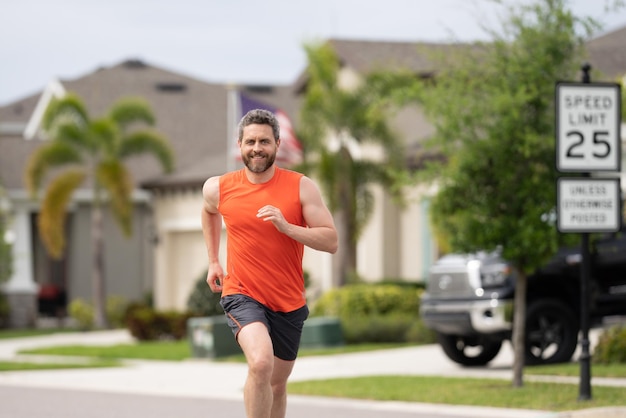 Mann, der auf der Straße in der Nachbarschaft läuft Schöner Athlet, der auf der Straße läuft Mann in Sportbekleidung Runni