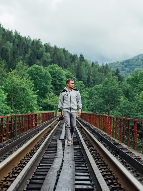 Mann, der auf einer Eisenbahnbrücke im Wald geht