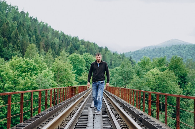 Mann, der auf einer Eisenbahnbrücke im Wald geht