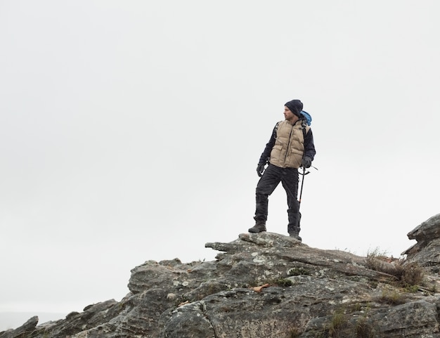 Mann, der auf Felsen gegen den klaren Himmel steht