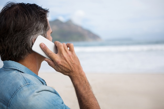 Mann, der auf Handy am Strand spricht