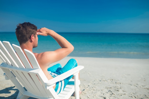 Mann, der auf Klappstuhl am Strand sich entspannt