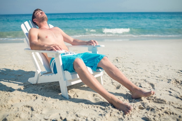 Mann, der auf Klappstuhl am Strand sich entspannt