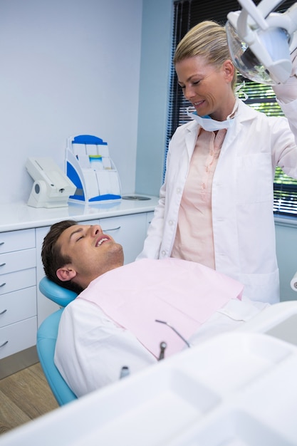 Mann, der auf Zahnarztstuhl liegt, während Doktor an Klinik steht