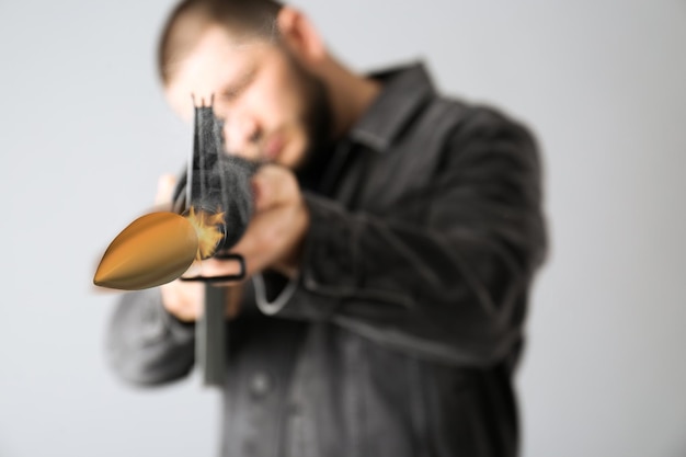 Mann, der aus Sturmgewehr auf hellem Hintergrund schießt, konzentriert sich auf Waffe