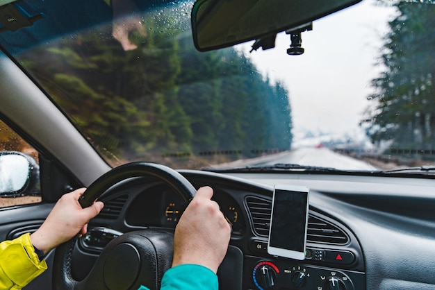 Mann, der Auto durch verschneite Gebirgsstraße fährt