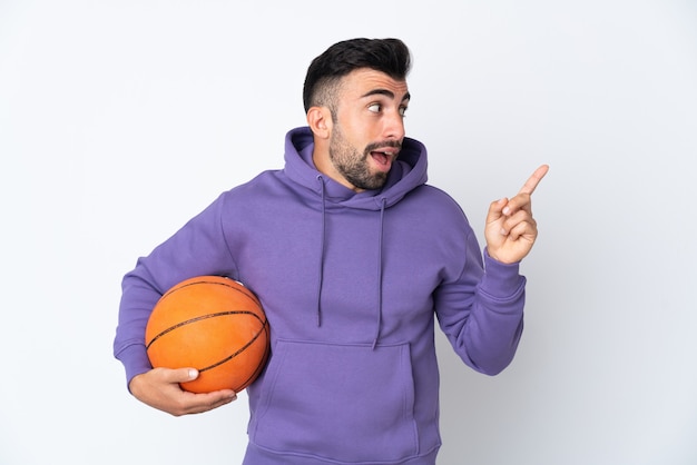 Mann, der Basketball über isolierte weiße Wand spielt, die beabsichtigt, die Lösung zu realisieren, während er einen Finger anhebt