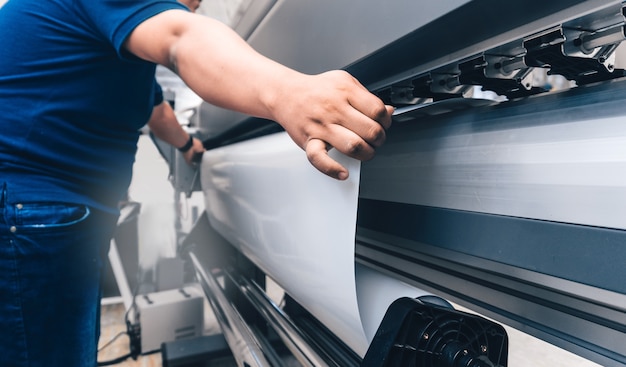 Foto mann, der bedruckbares material auf einem großformatigen druckplotter hält