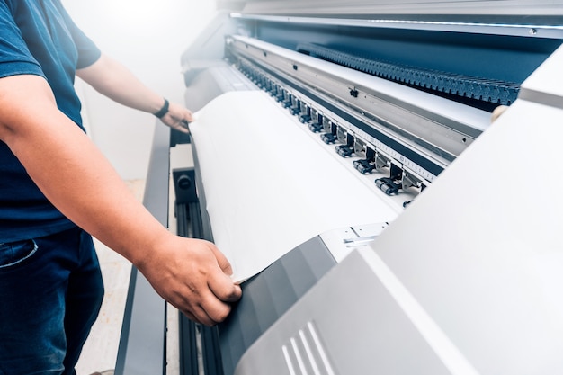 Foto mann, der bedruckbares material auf einem großformatigen druckplotter hält