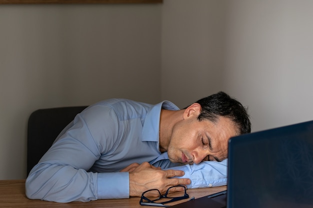 Mann, der bei der Arbeit mit seinem Laptop schläft